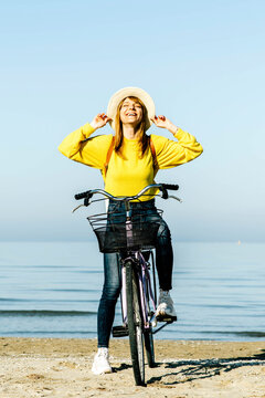 Happy woman standing with bicycle on footpathat the sea