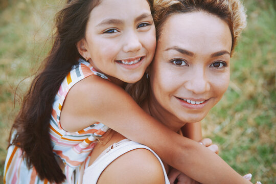 Smiling mother giving piggyback ride to daughter