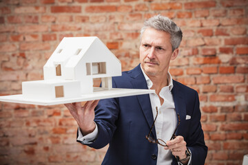 Male entrepreneur with eyeglasses looking at architectural model in office