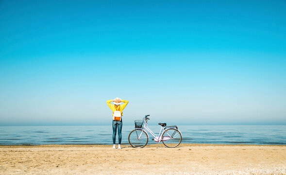 Woman looking at view while standing by bicycle on beach