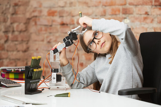Girl doing scientific experiment on robotic arm at table