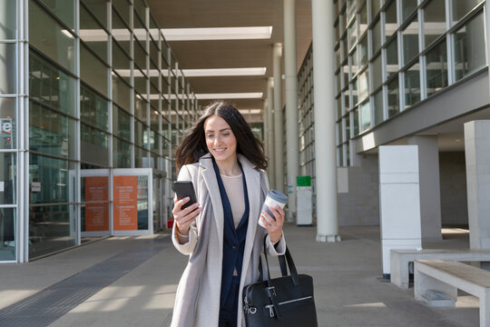 Young female entrepreneur using mobile phone while standing on footpath