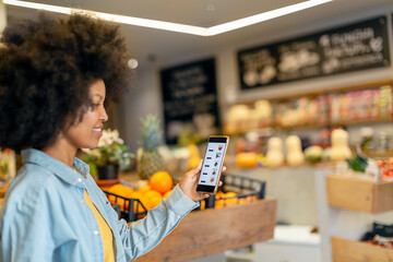Afro woman using mobile application in grocery store