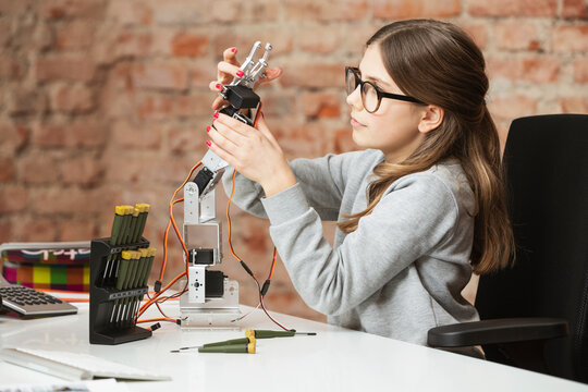 Girl building robotic arm while sitting at table