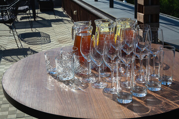 A set of empty glasses displayed in rows and a decanters of cool lemonade or juice for the party or wedding. Summer refreshing fruit-drink from apples and lemons. Berry drinks on the table.