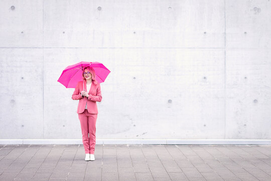 Young woman with umbrella standing on footpath
