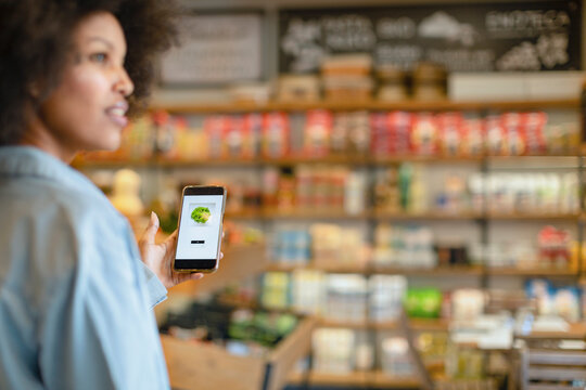 Woman buying vegetables through mobile application in supermarket