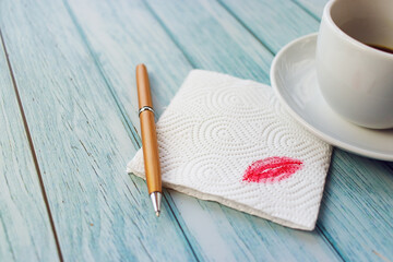 A napkin with a red kiss with a handle on a light table in a close-up, a wooden table in blue