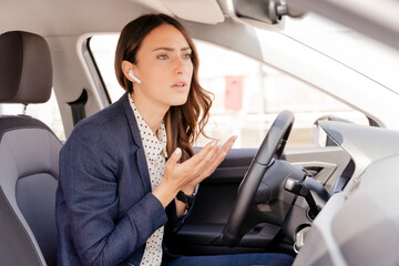 Worried businesswoman talking on call while gesturing in car