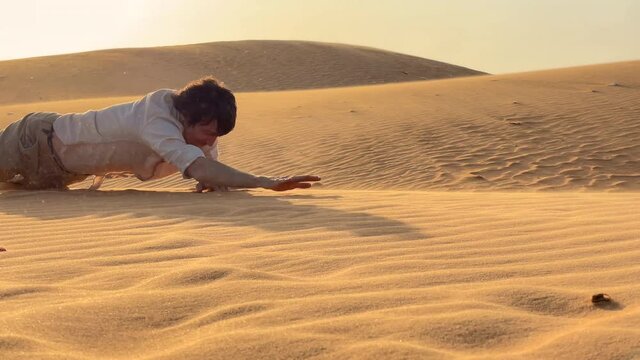 A man in an office cloth crawls up a dune in a desert. Overcoming challenges in business