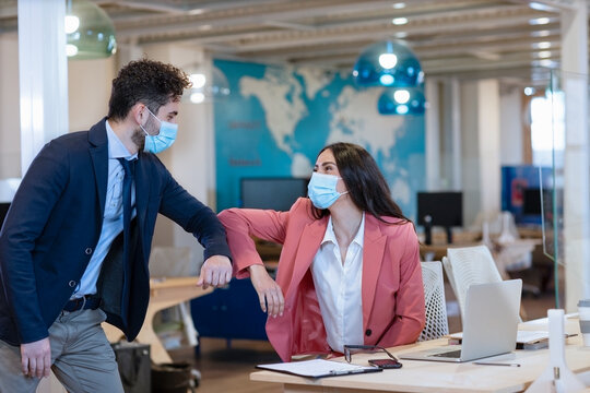 Male and female entrepreneurs doing elbow bump during pandemic at office