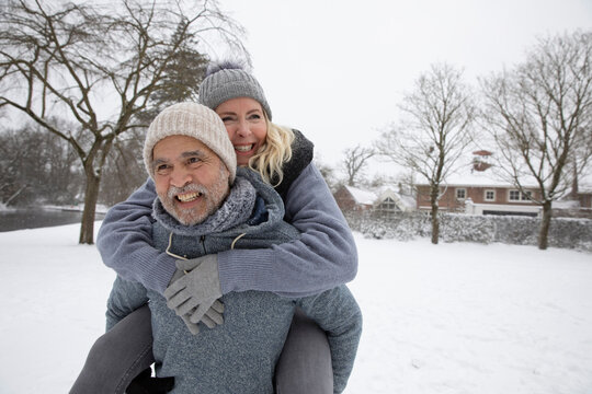 Senior man piggybacking woman at park during winter