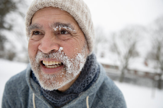 Smiling man looking away with snow on face during winter