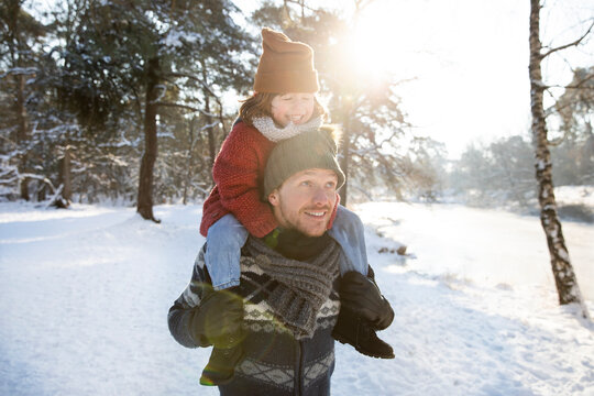 Father carrying son on shoulder in winter during sunny day