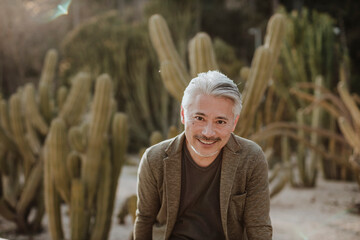 Smiling mature man with cactus garden in background