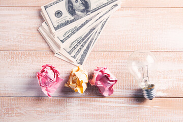 light bulb, crumpled papers and money