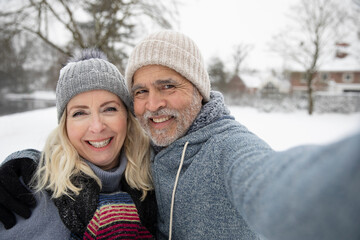 Man embracing woman while taking selfie during winter