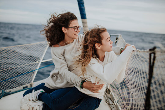 Mother and daughter looking at view while traveling through sailboat in sea during vacation