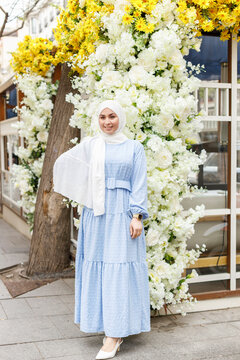 Smiling woman wearing hijab standing on footpath