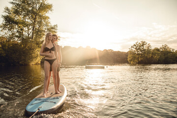Young couple enjoying summer at the lake, standing on a paddleboard