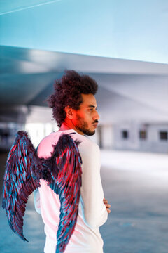 Young man with angel wings looking away
