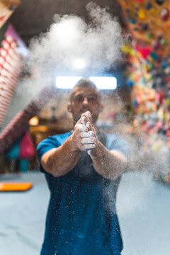 Young sportsman dusting talcum powder on hands in health club