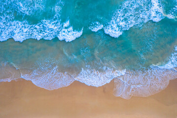 Fototapeta na wymiar aerial top view Wave after wave swept towards the shore. . white foamy waves crash along the beach..Beach sea space area. Blue sea, waves crashing at Karon Beach, Phuket.