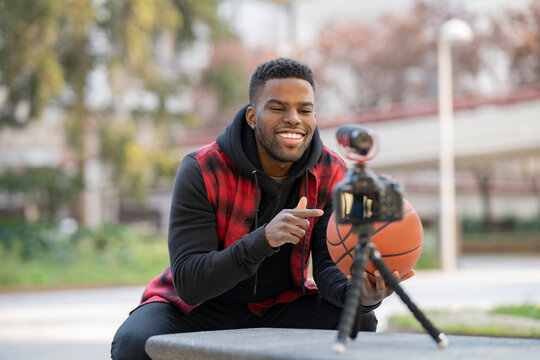 Handsome young influencer vlogging while pointing at basketball