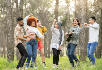 Male and female friends dancing and enjoying at forest