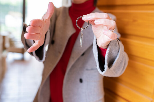 Woman offering handshake while holding house key at front door