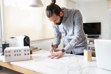 Male architect designing construction plan while working at home