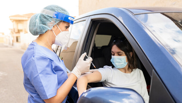 Mid adult woman getting vaccinated from female doctor in car