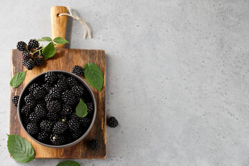 Ripe blackberries with leaves in bowl on gray background - Powered by Adobe