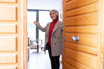 Smiling woman welcoming guest at front door of house