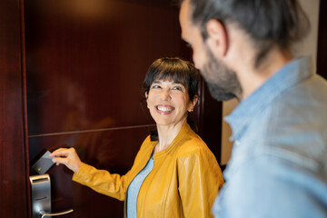 Smiling woman opening door with card key in hotel