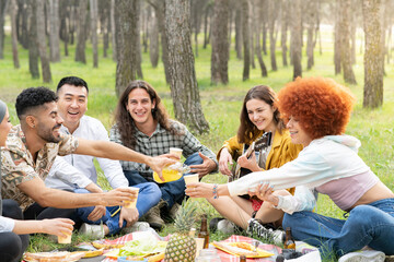 Cheerful male and female friends enjoying party in picnic at forest