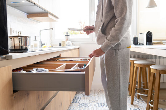 Man opening drawer in kitchen at home
