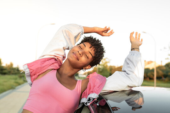 Woman with arms raised enjoying wind while travelling by car