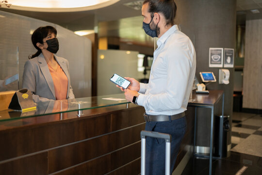 Mature man wearing protective face mask standing at receptionist desk