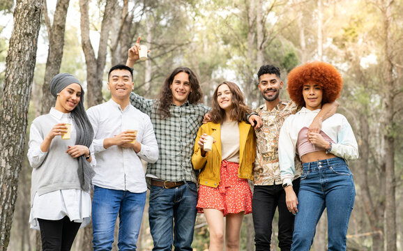 Cheerful male and female friends holding reusable glass in forest