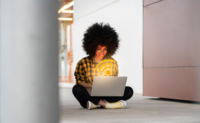 Afro woman using laptop with digitally generated WIFI logo