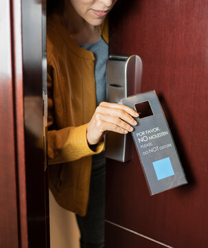 Woman adjusting do not disturb sign label at hotel