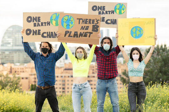 Men with women holding banner amidst plants in city during pandemic