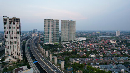 Aerial view of highway intersection and buildings in the city of Bekasi and noise cloud with Bekasi cityscape. Bekasi, Indonesia, June 18, 2021
