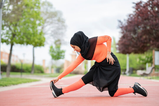 Arab woman stretching in public park - Powered by Adobe