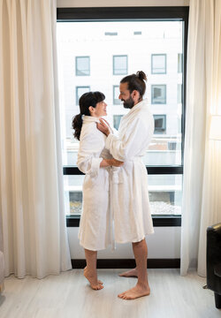 Mature couple wearing bathrobes standing by window