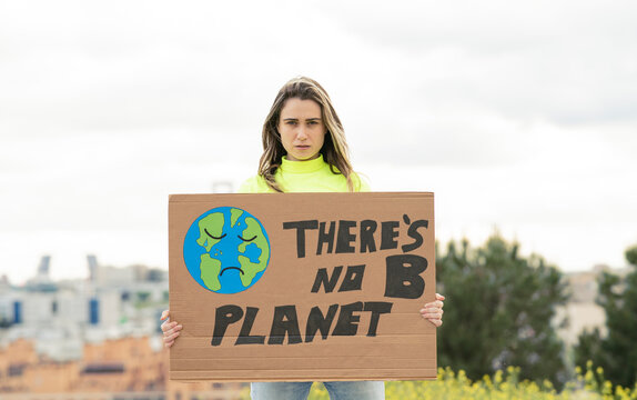Woman with climate change poster standing in front of sky