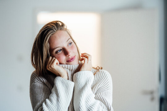 Beautiful woman in sweater looking away at home