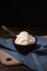 Bowl with homemade vanilla ice cream balls on a dark wooden background, rustic style.