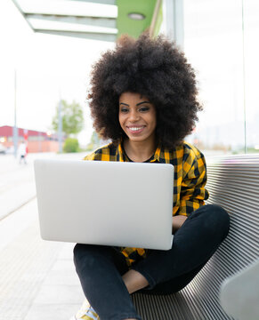 Woman using laptop while sitting on bench outdoors